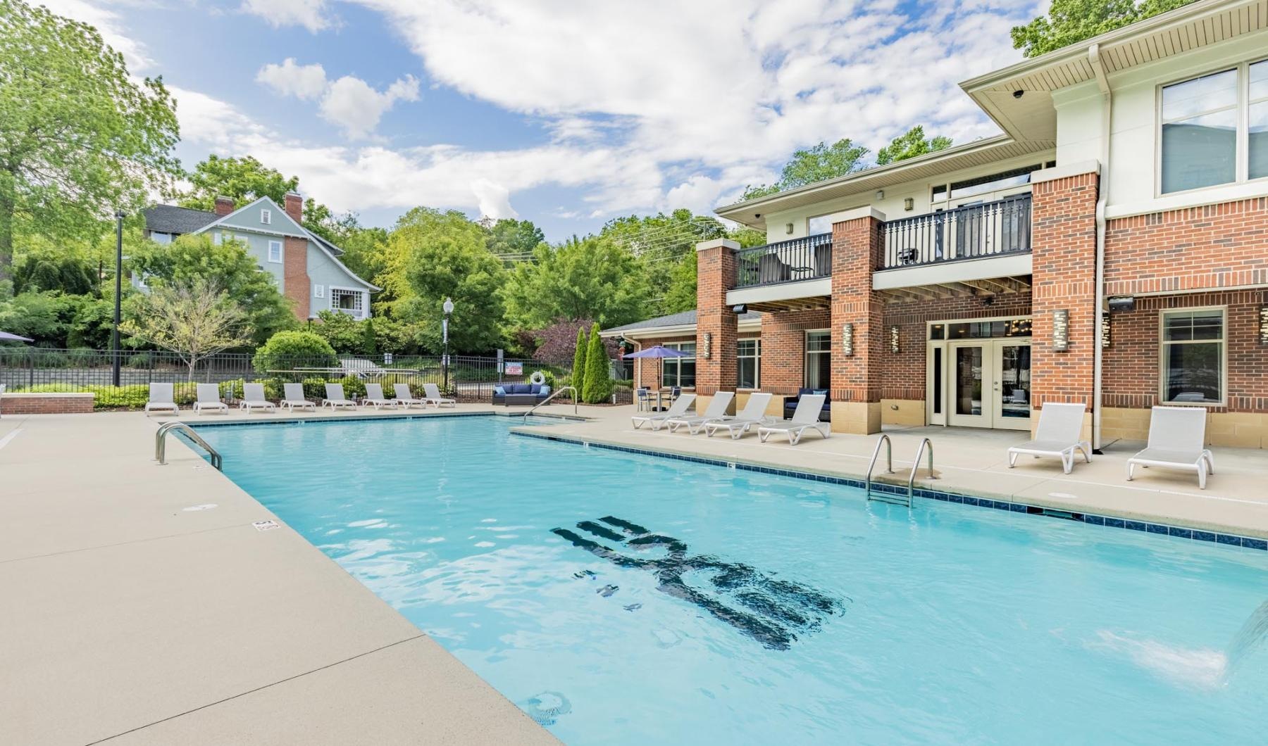 a swimming pool with chairs and a building in the background